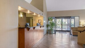 A reception area with a wooden counter, a potted plant, and a view through a glass door. - Sleep Inn & Suites Bakersfield North (Bakersfield)