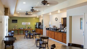 A dining area with tables and chairs, a kitchen area with appliances, and a clock on the wall. - Sleep Inn & Suites Bakersfield North (Bakersfield)