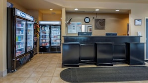 A reception area with a counter, two refrigerators stocked with beverages, and a clock on the wall.
