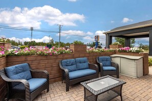 Un espacio al aire libre con patio, mobiliario de mimbre, una barra y macetas con flores.