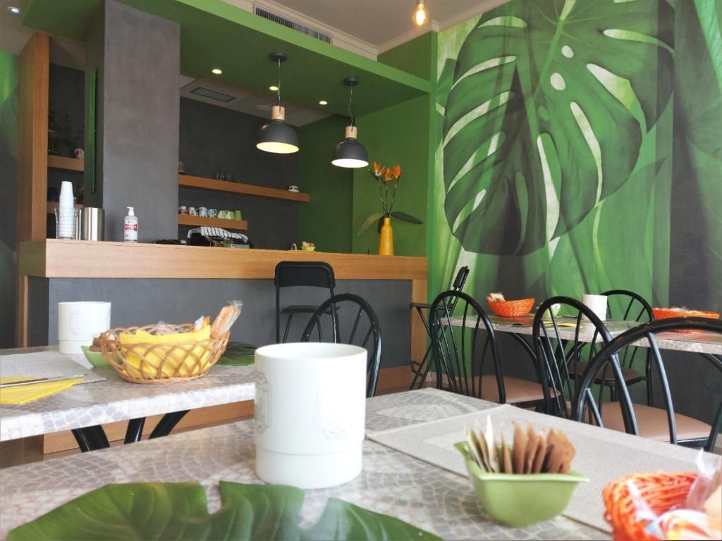 A restaurant interior with a green wall mural, wooden counter, and black chairs.