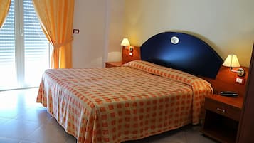 A hotel room with a bed, two bedside lamps, a nightstand, and a window with curtains.