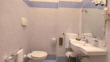 Une salle de bain équipée de toilettes, d’un bidet, d’un lavabo et d’un miroir.