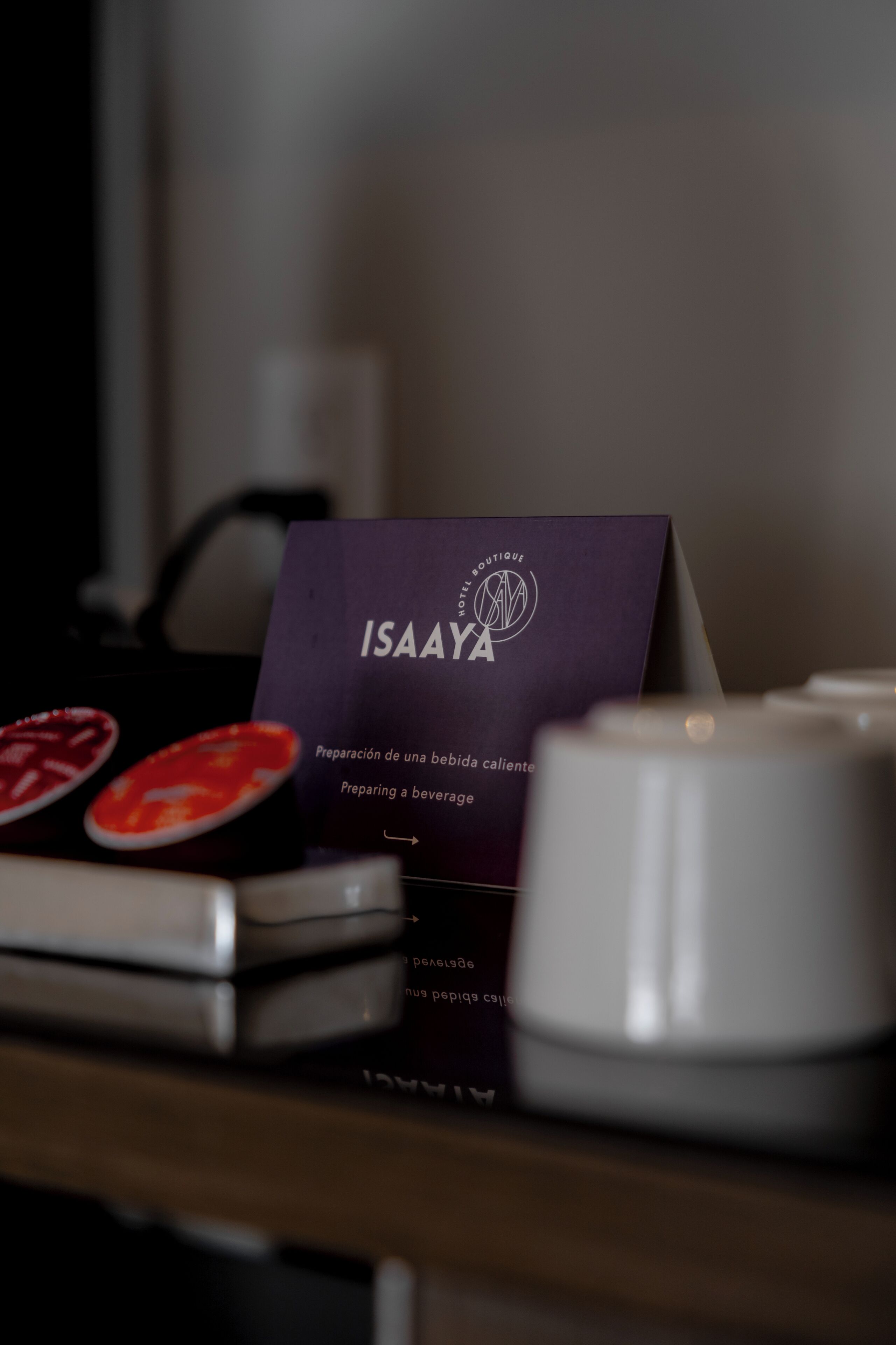 Eine Visitenkarte des ISAAYA Hotel Boutique mit einem Logo und einer weißen Kerze auf einem Tisch.