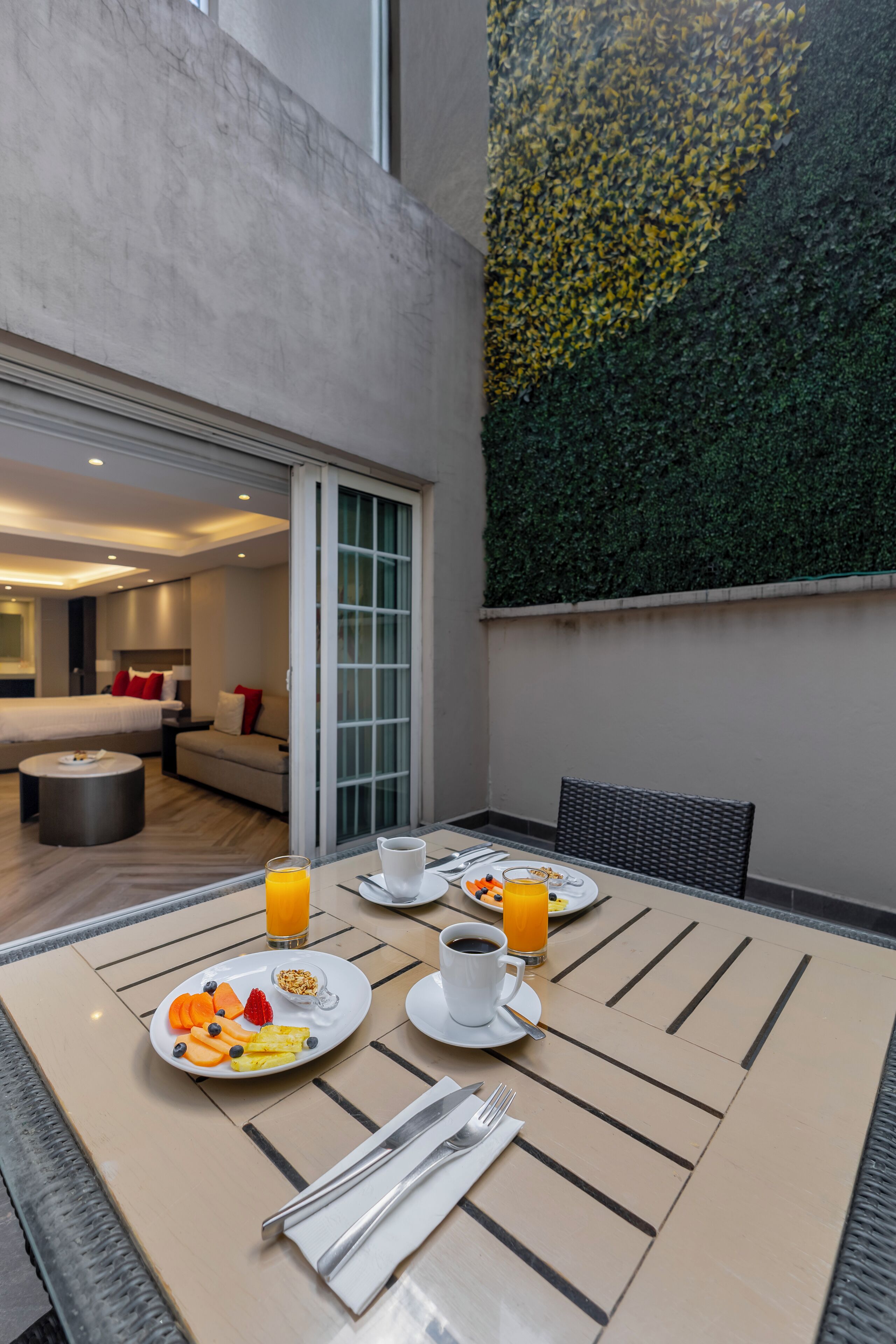 A dining area with a table set for breakfast, a sofa, and a sliding glass door leading to a bedroom.