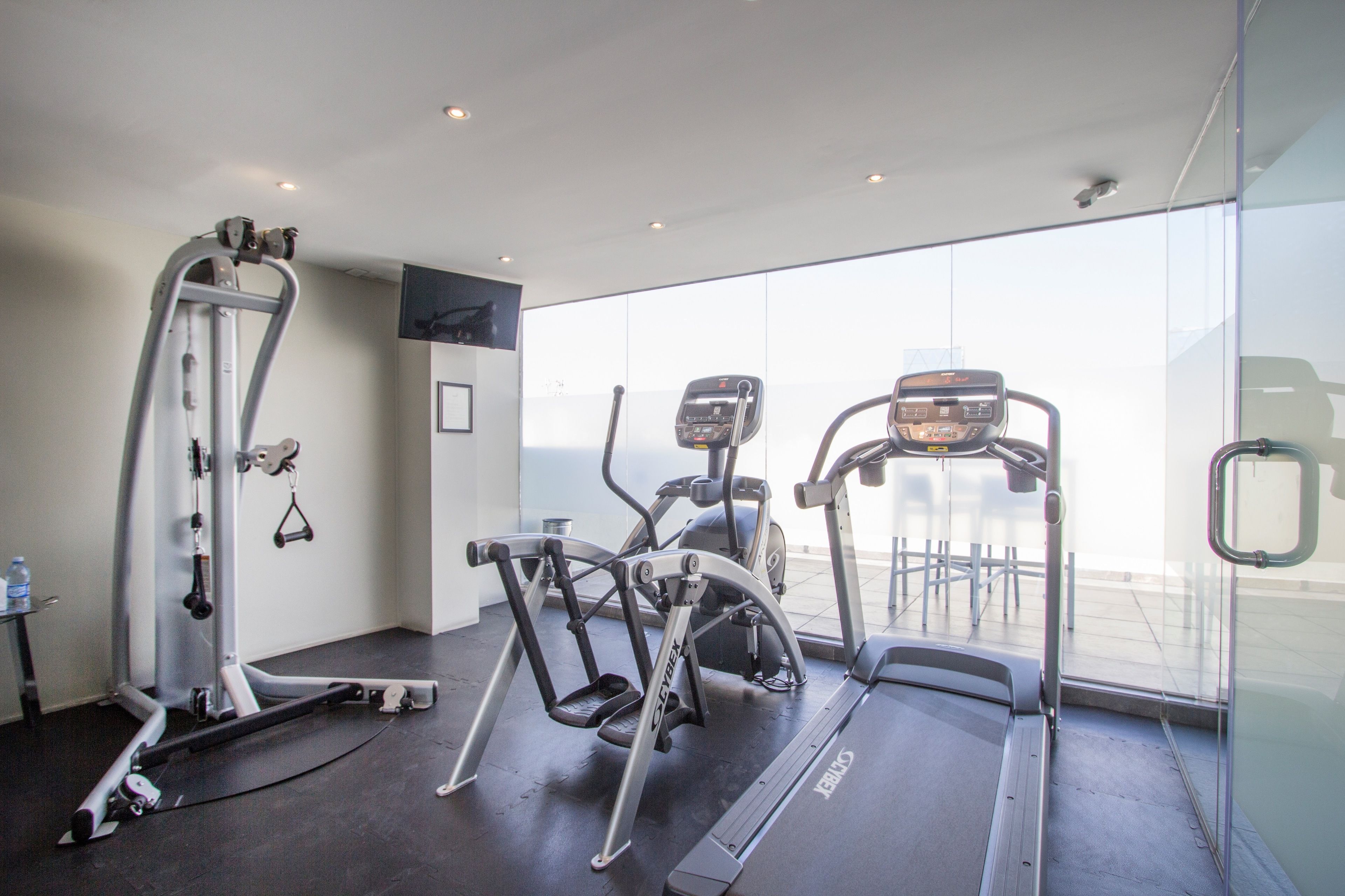 Une salle de sport équipée de tapis de course, de vélos elliptiques et d’appareils de musculation.