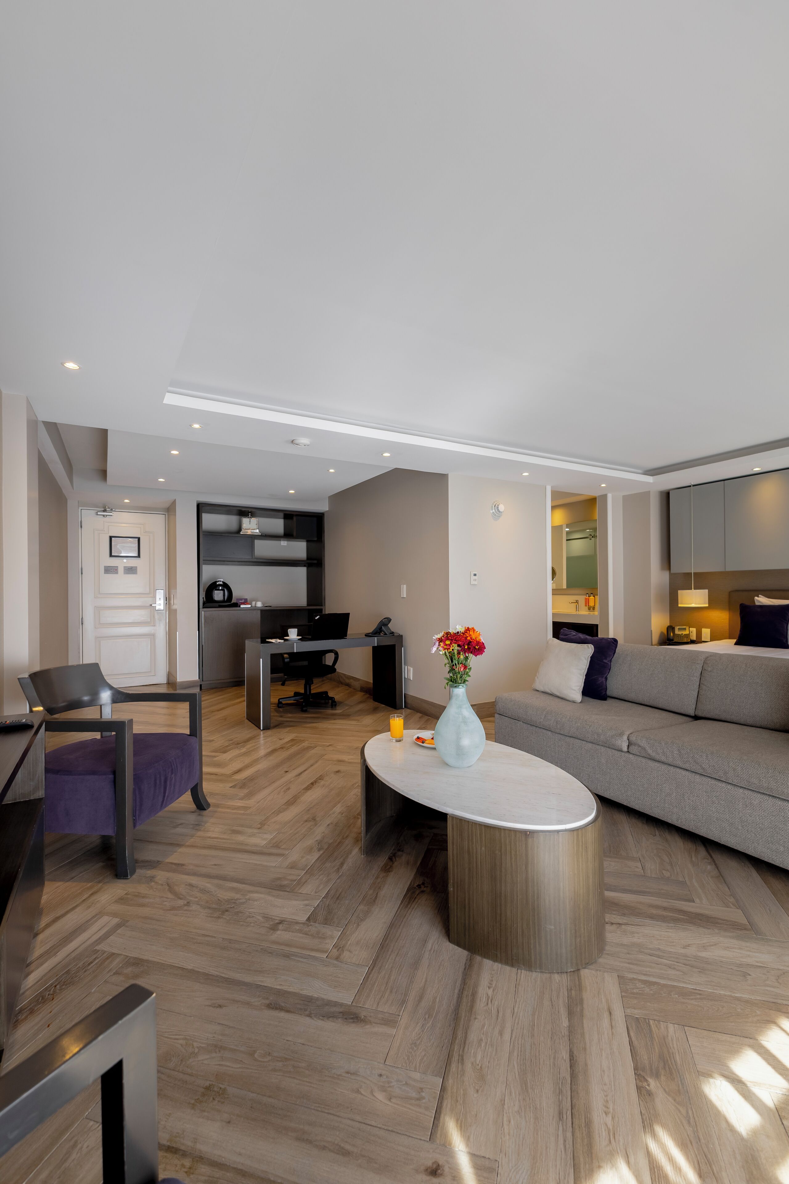 A modern living room with a sofa, a coffee table, and a dining area.