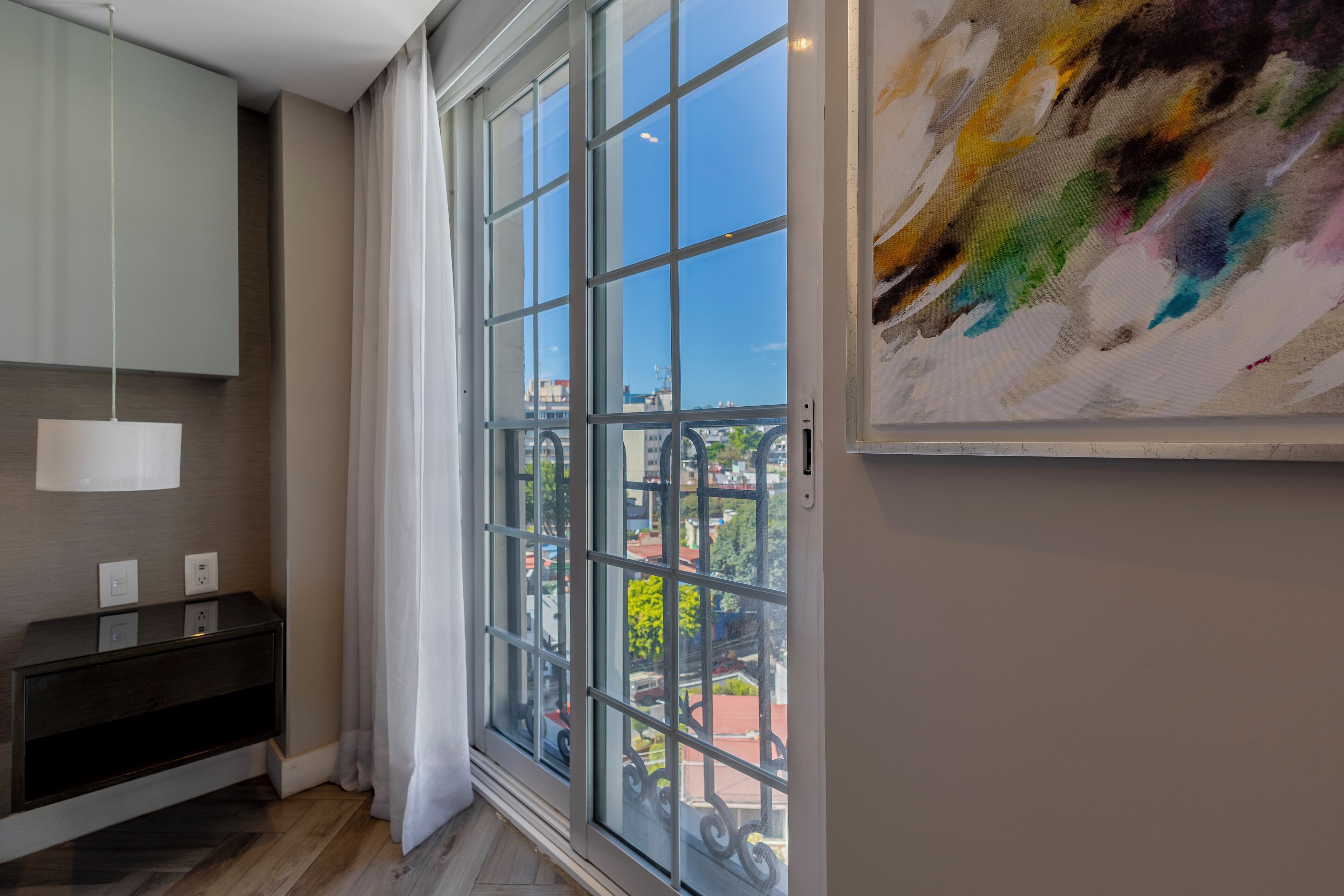 Une pièce moderne avec une grande fenêtre, une console sombre et un tableau accroché au mur.