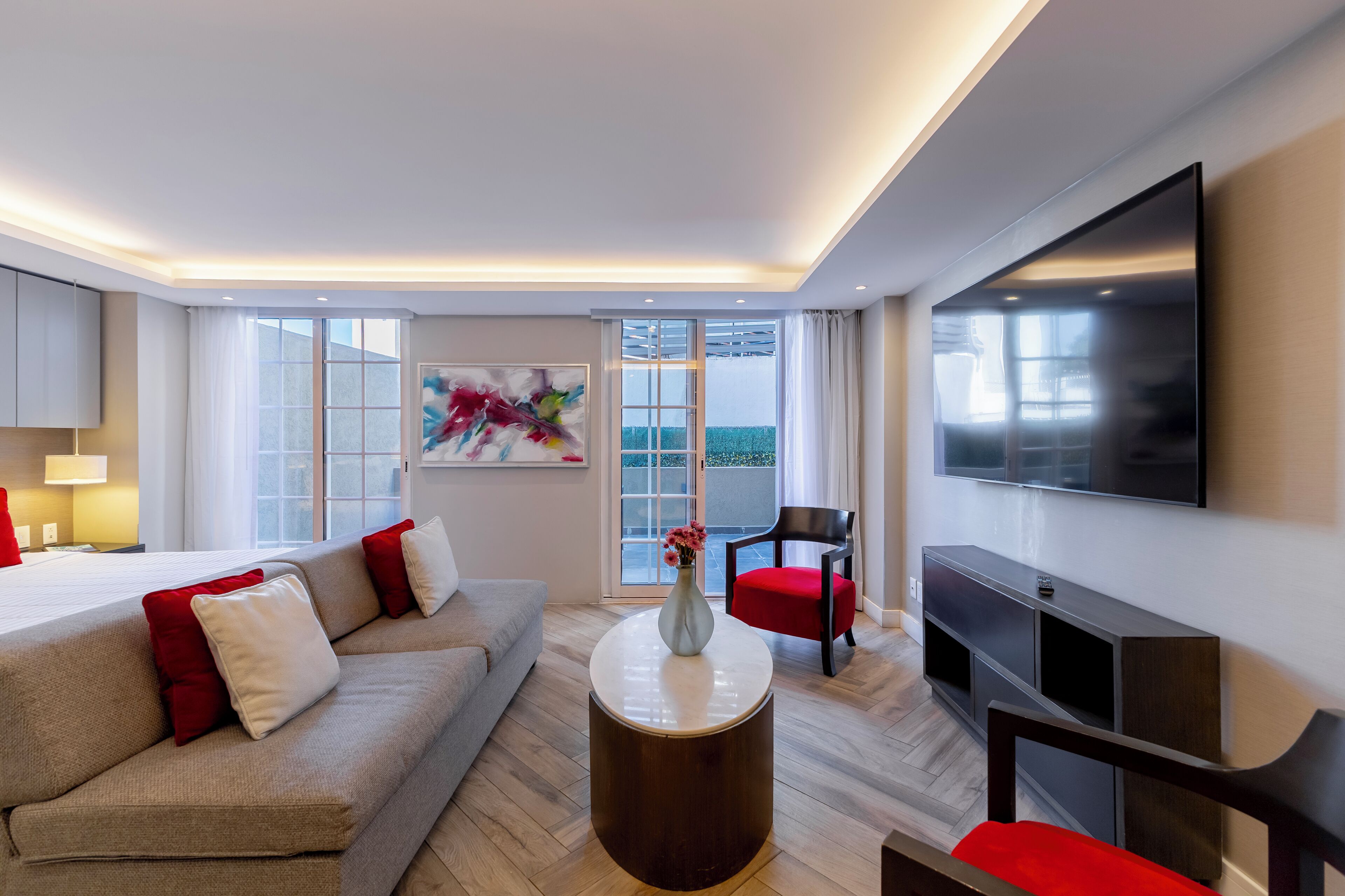Une chambre d’hôtel moderne équipée d’un lit, d’un canapé, d’une table basse, d’une télévision et d’un balcon avec vue.