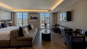 Una habitación de hotel moderna con una cama grande, un sofá, una mesa de centro y un televisor.