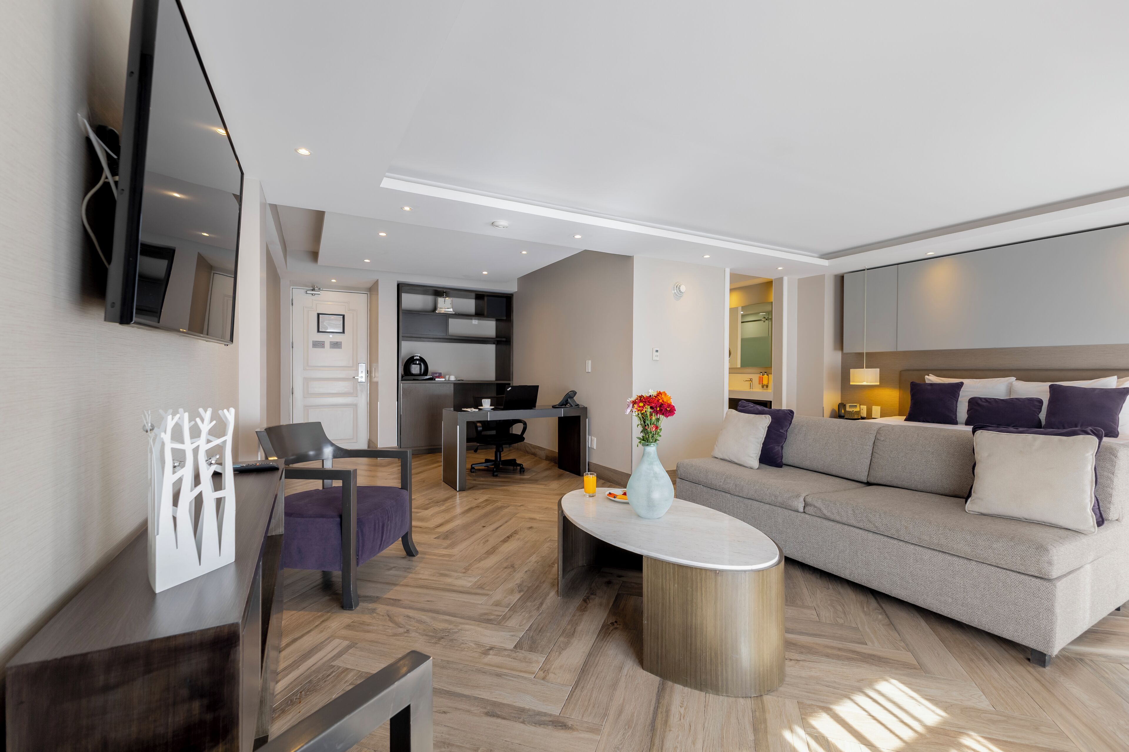 A modern living room with a sofa, coffee table, and a dining area with a chair.
