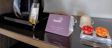 Un minibar con una cafetera, un vaso de agua, una taza de café y un cartel de ISAAYA.