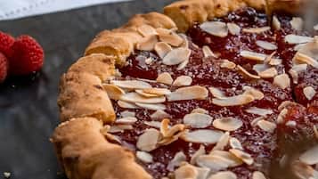 Una tarta de cerezas con almendras sobre una superficie oscura.