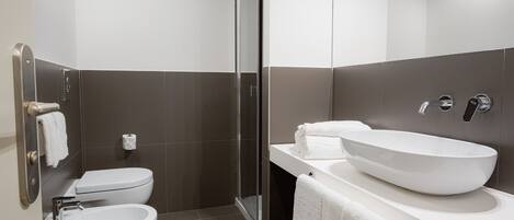A modern bathroom with a toilet, bidet, and a large sink.