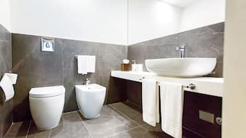 A modern bathroom with a toilet, bidet, and a large sink with a marble countertop.
