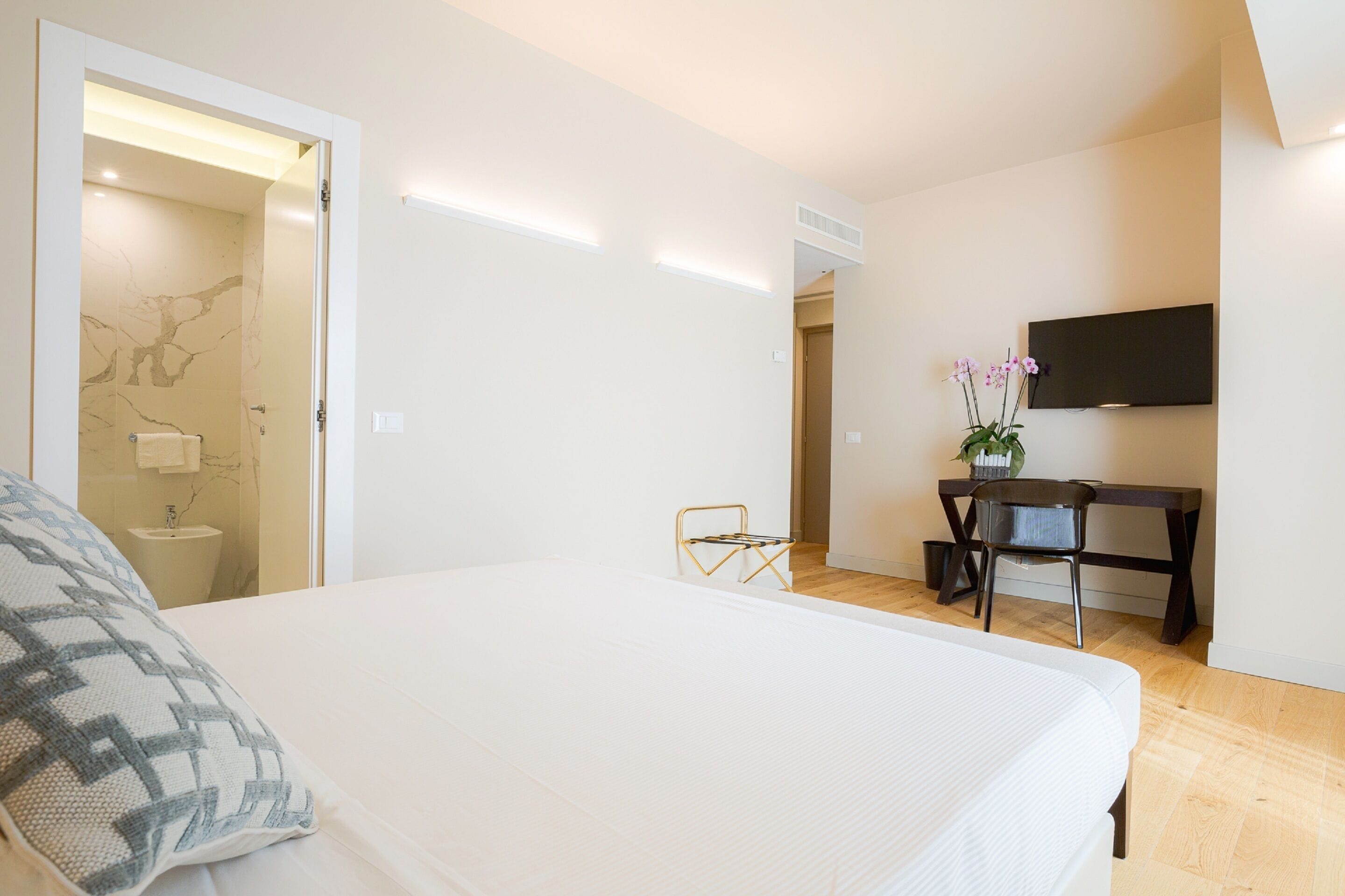 A bedroom with a large bed, a desk, and a TV.