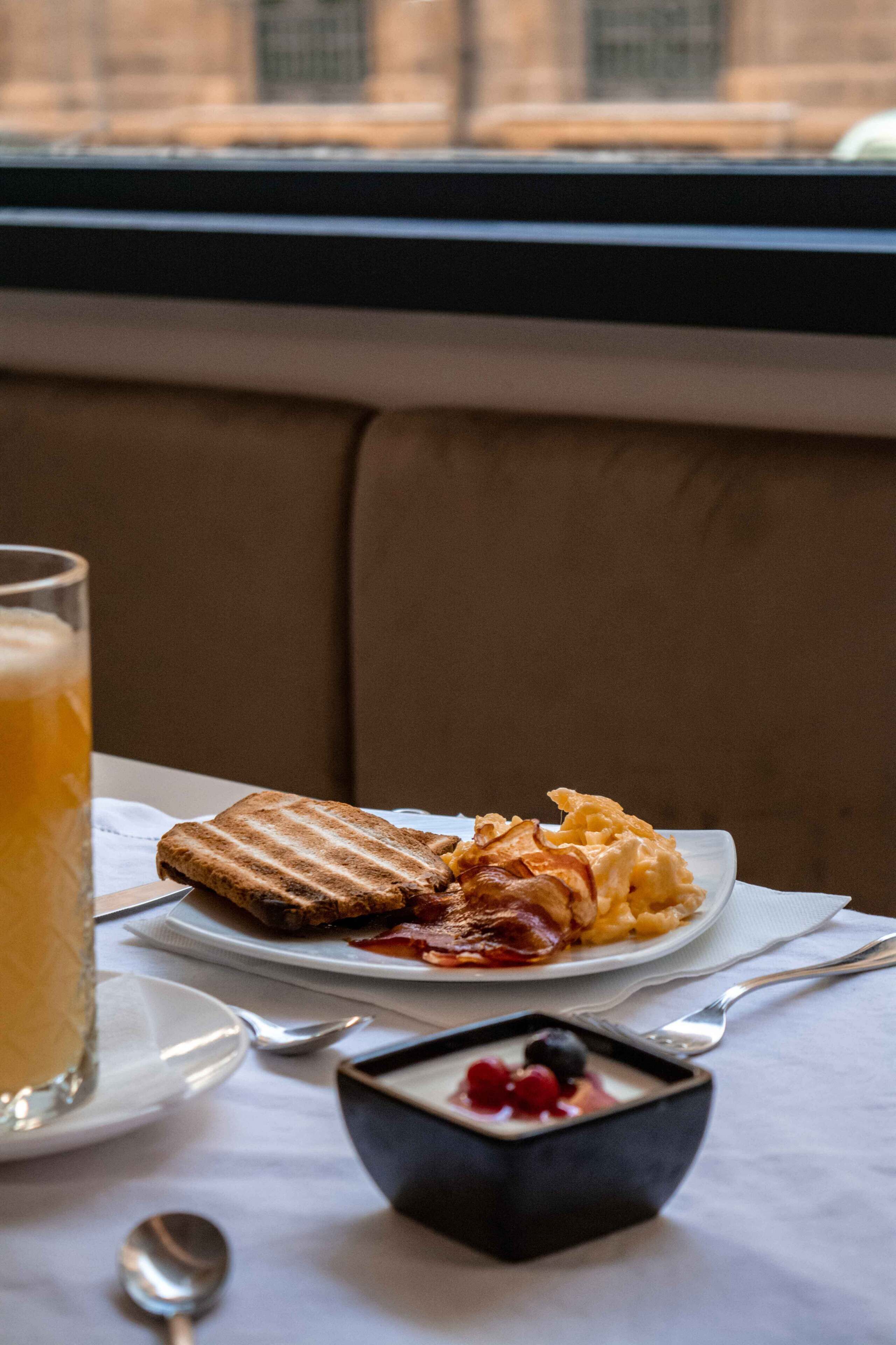 A breakfast setting with toast, scrambled eggs, and a glass of orange juice on a table.