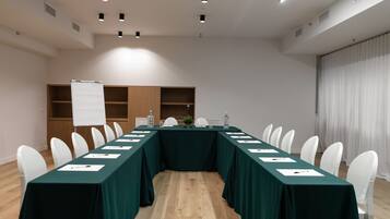 A conference room with a long table, white chairs, and a whiteboard.