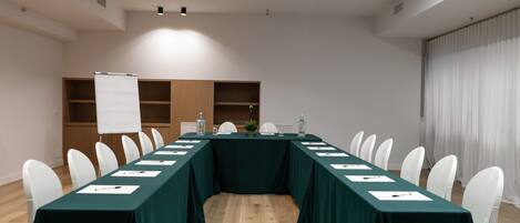 A conference room with a long table, white chairs, and a whiteboard.