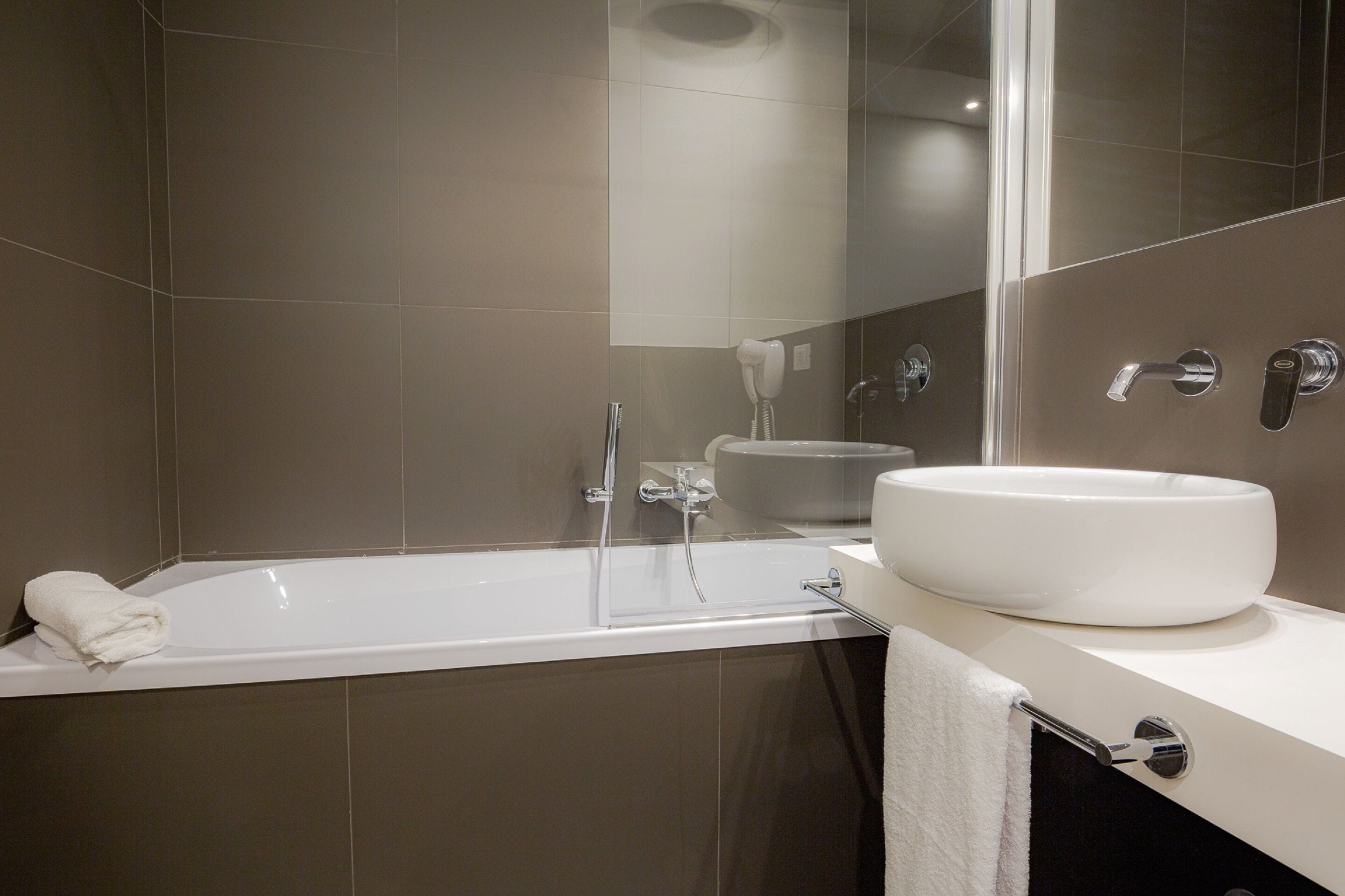 A modern bathroom with a bathtub, a sink, and a mirror.