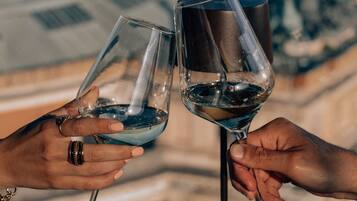 Two hands holding wine glasses with a view of buildings in the background.