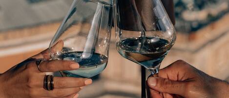 Two hands holding wine glasses with a view of buildings in the background.