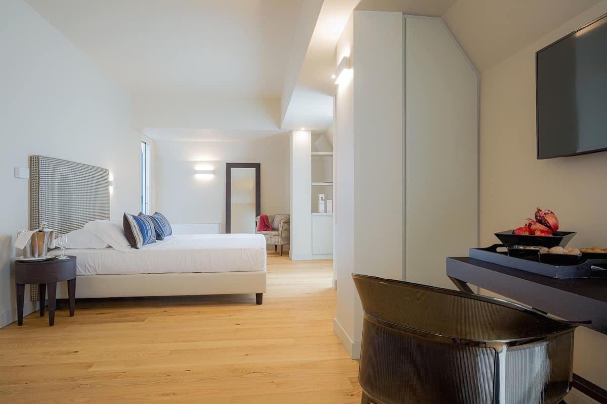 Una habitación de hotel moderna con una cama, una mesita de noche y un televisor montado en la pared.