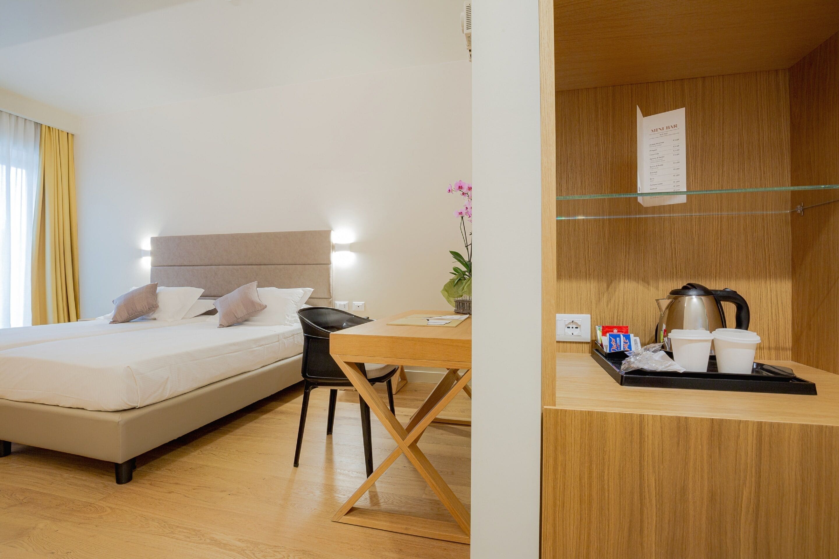 Habitación de hotel con cama, escritorio, silla, una mesita y zona de kitchenette.