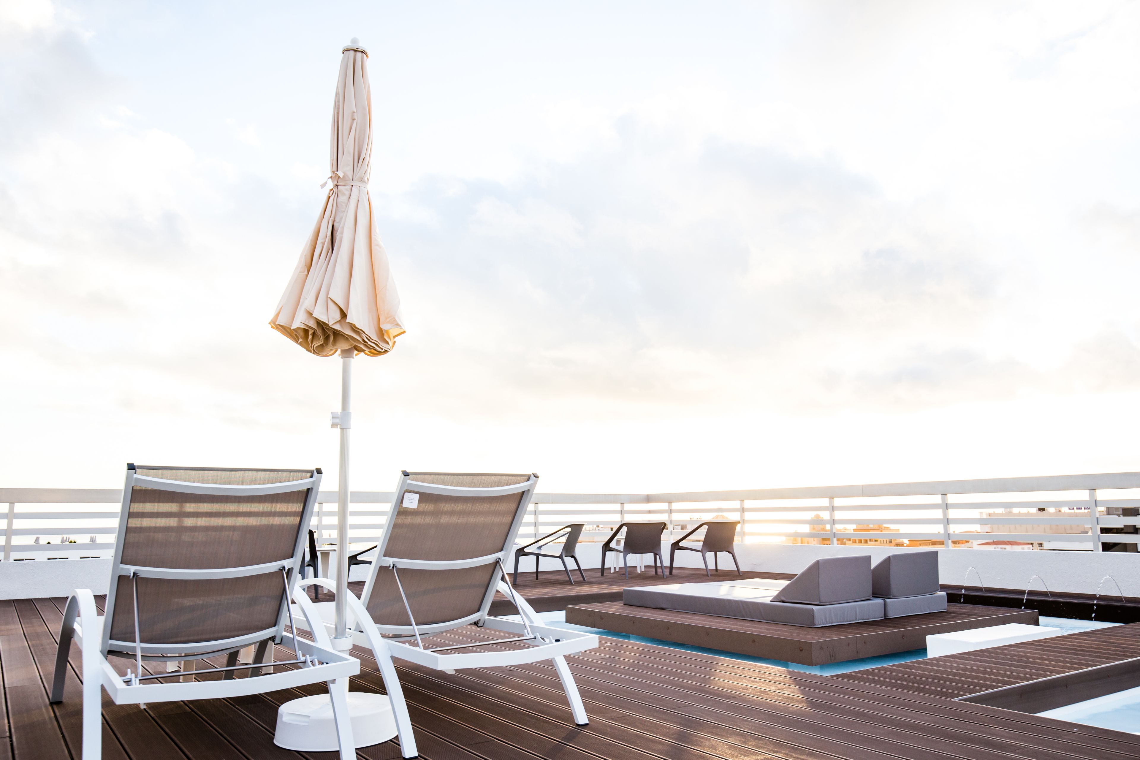 A sun deck with lounge chairs, a pool, and a view of the ocean.