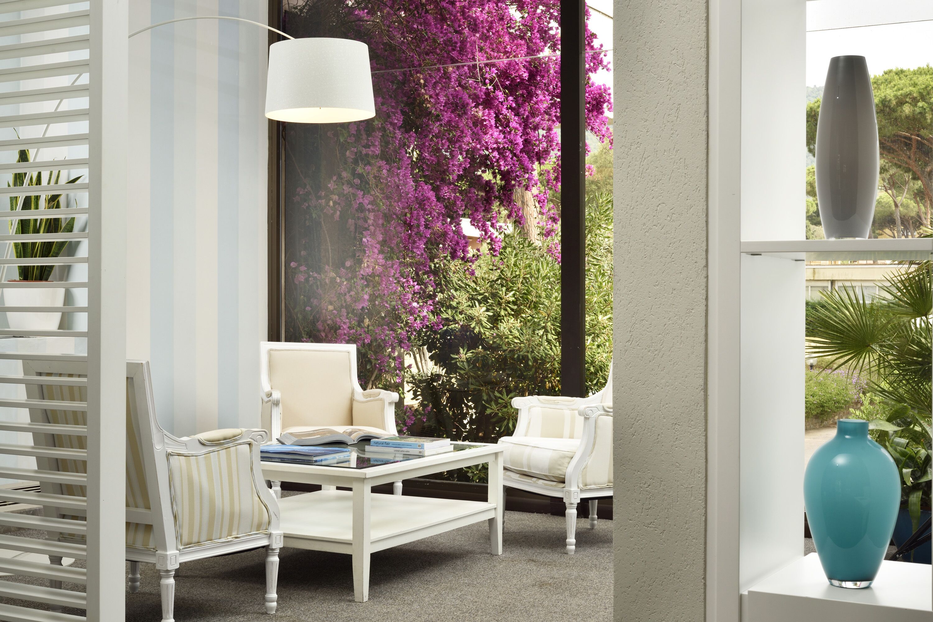 Ein weißer Fensterrahmen mit Blick auf violette Blumen und Grünpflanzen.