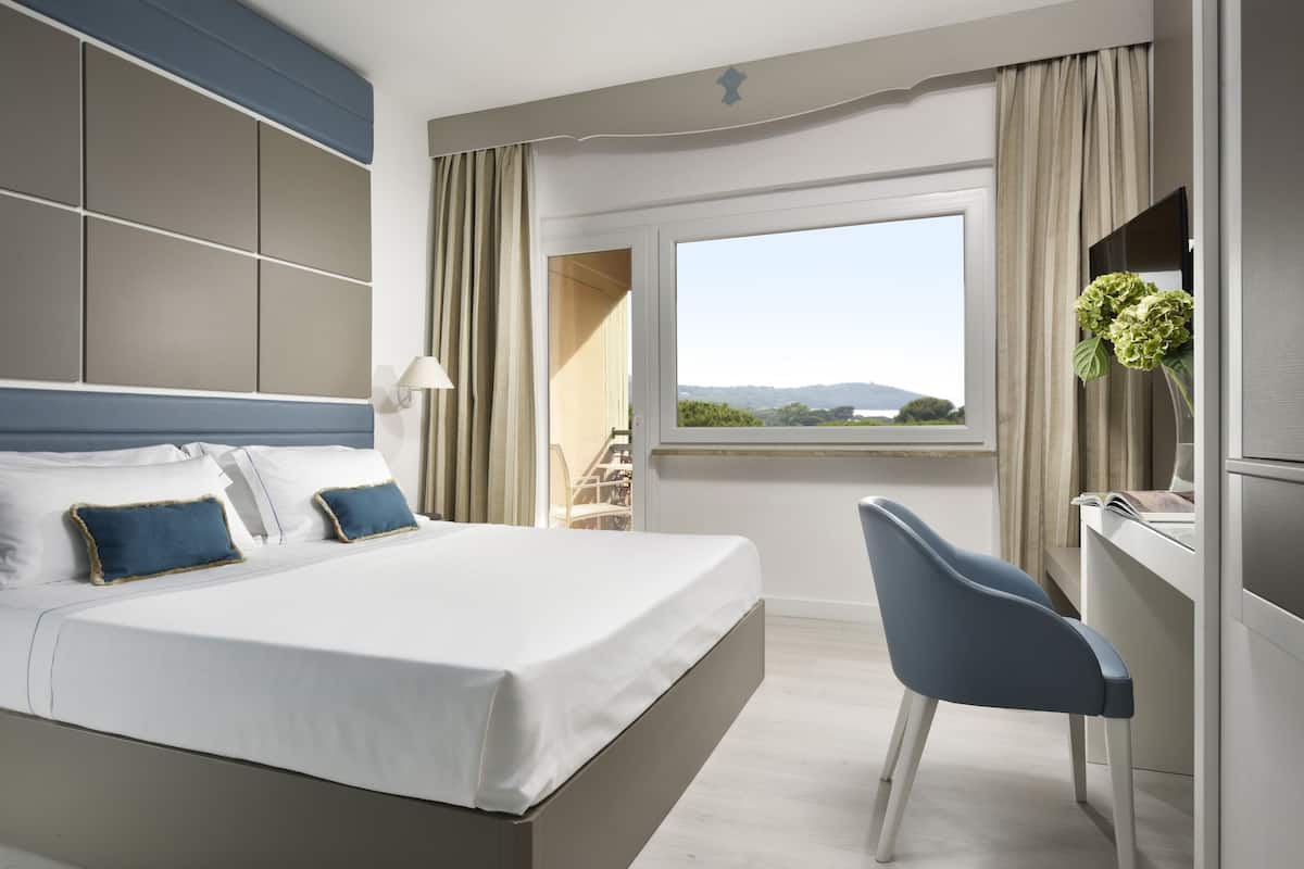 Una habitación de hotel moderna con una cama grande, un escritorio y vistas al exterior.