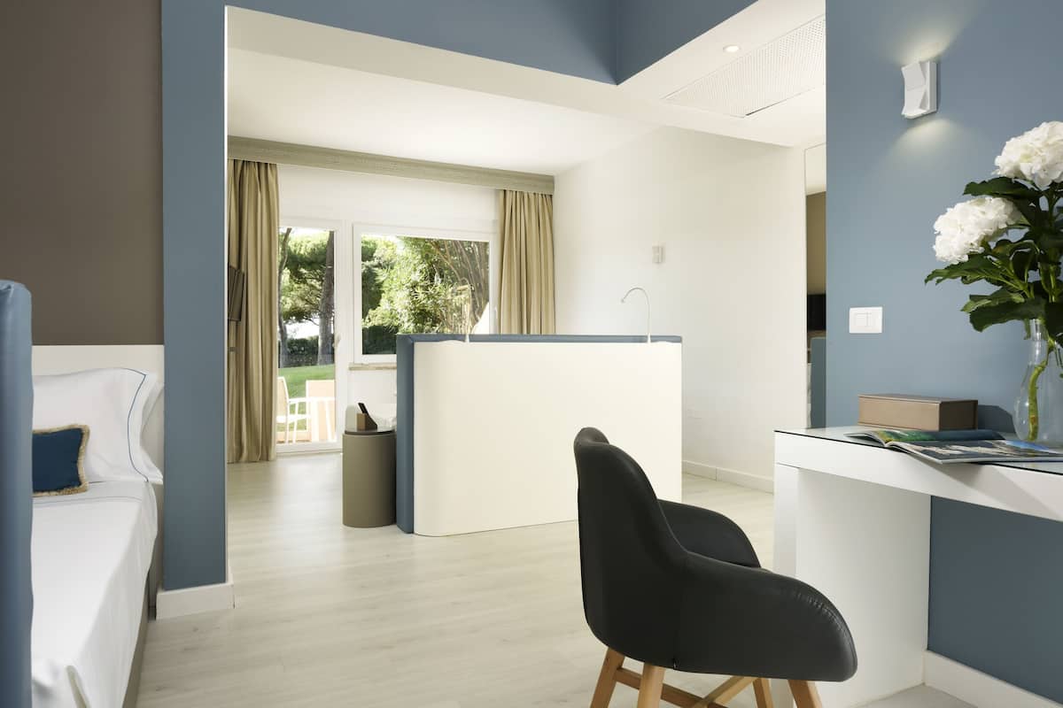 Una habitación de hotel moderna con una cama, un escritorio y vistas al exterior.