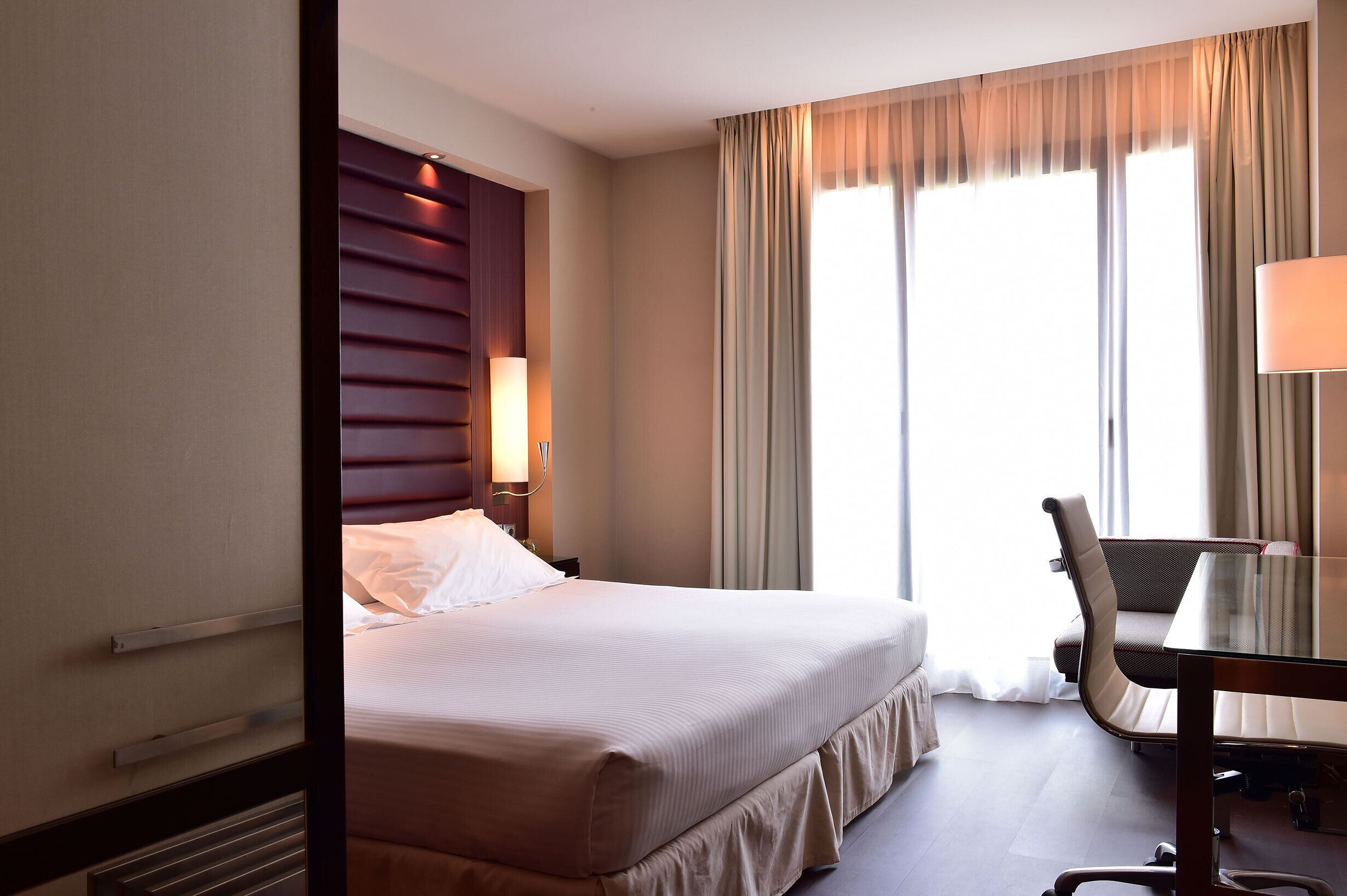 Ein Hotelzimmer mit Bett, Schreibtisch und Stuhl.