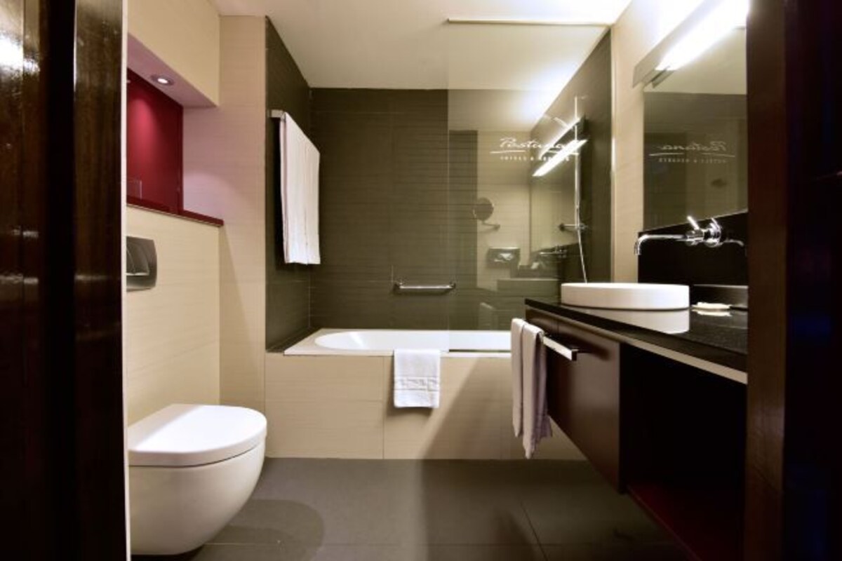 Une salle de bain moderne équipée de toilettes, d’une baignoire et d’un meuble-lavabo.