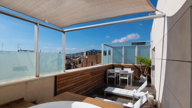 Terraza en la azotea con jacuzzi, cubierta de madera y zona de estar al aire libre.