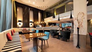 Un moderno vestíbulo de hotel con un sofá, zona de comedor y un bar.