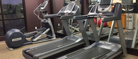 A gym with treadmills, elliptical machines, and a stationary bike.