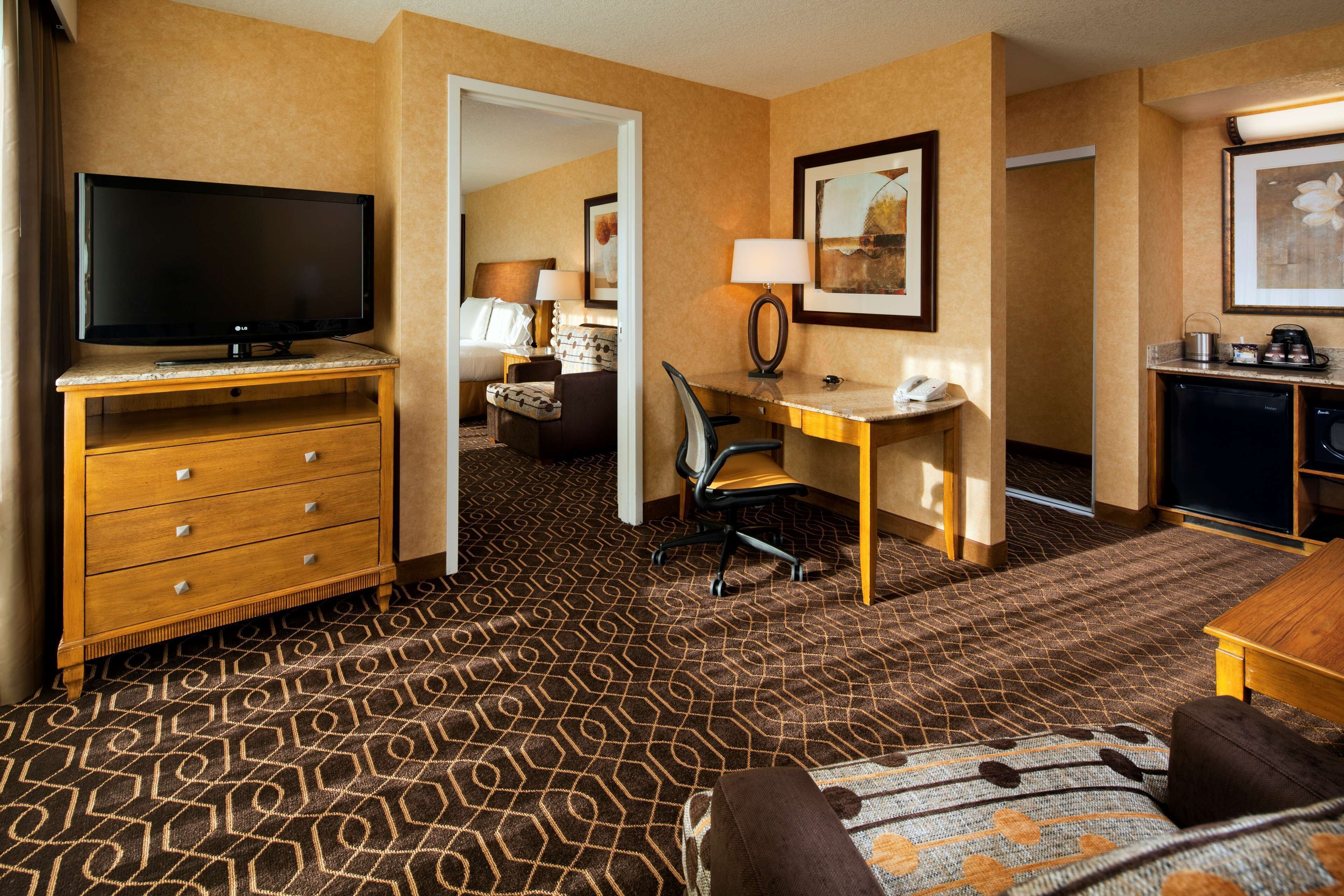 Habitación de hotel con televisión, escritorio, silla y cama.