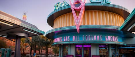 A vintage-themed building with neon signage, including "Flair's Cafe" and "Lick 'n' Go" signs.