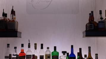 Angolo bar con diverse bottiglie di liquore e un cartello che indica 'Grappa Lounge'.