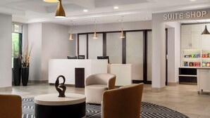 A modern hotel lobby with a reception desk, seating area, and a 'SUITE SHOP' sign. - Homewood Suites by Hilton-Hartford South-Glastonbury, CT (Glastonbury)