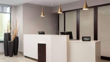 A modern hotel reception desk with two pendant lights, a large window, and a sign indicating 'Hilton Honors'.