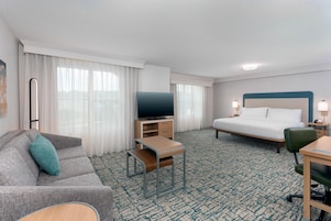 A hotel room with a bed, a TV, a sofa, a desk, and a chair.