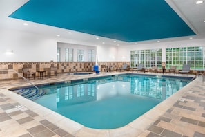 An indoor swimming pool with tiled flooring, a blue ceiling, and seating areas with tables and chairs. - Homewood Suites by Hilton Holyoke-Springfield/North (Holyoke)