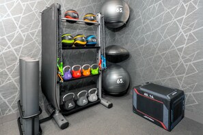 A gym with various exercise equipment including kettlebells, medicine balls, and a squat rack. - Homewood Suites by Hilton Holyoke-Springfield/North (Holyoke)