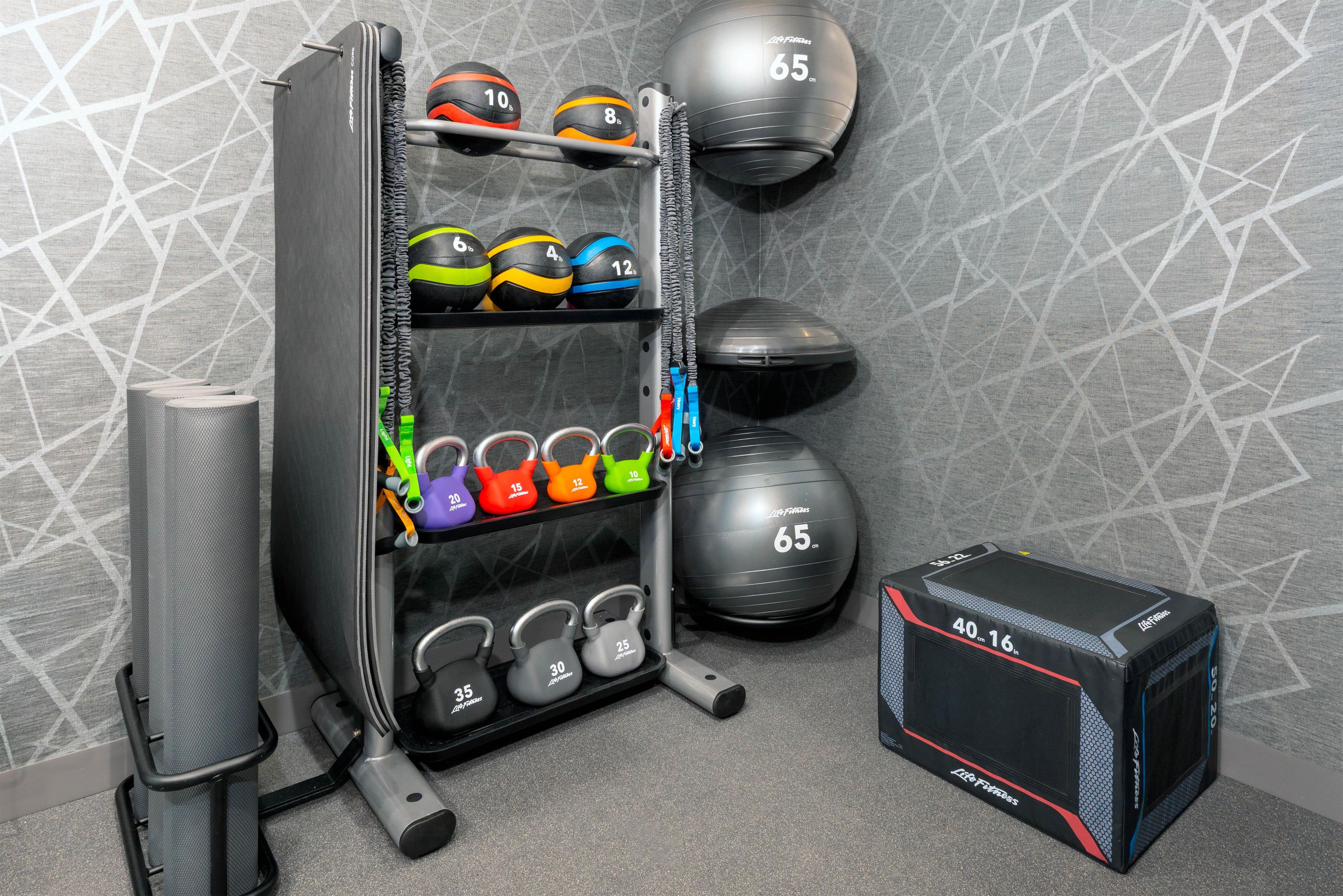 A gym with various exercise equipment including kettlebells, medicine balls, and a squat rack.