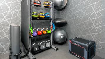 A gym with various exercise equipment including kettlebells, medicine balls, and a squat rack.