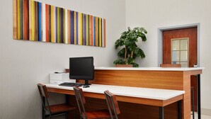 A reception desk with a computer, two chairs, a plant, and a colorful artwork on the wall. - Holiday Inn Express Hotel & Suites Panama City-Tyndall by IHG (Panama City)