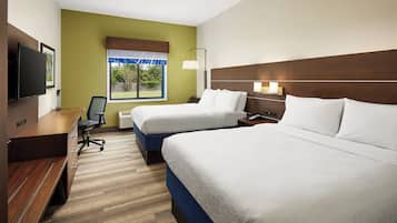 A hotel room with two beds, a desk, a chair, a TV, and a window with a view of greenery.