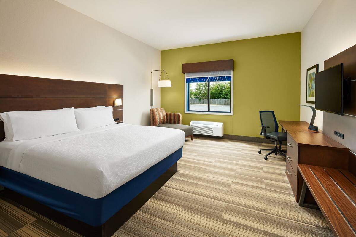 Ein Hotelzimmer mit Bett, Schreibtisch, Stuhl und Fernseher.